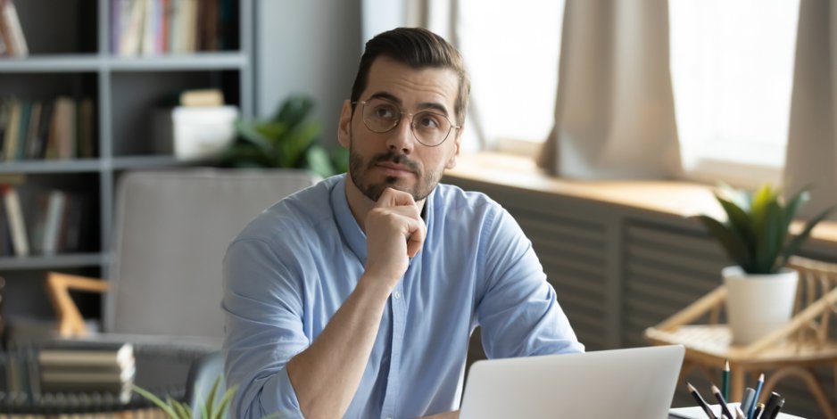 man at home doing computer research, wondering