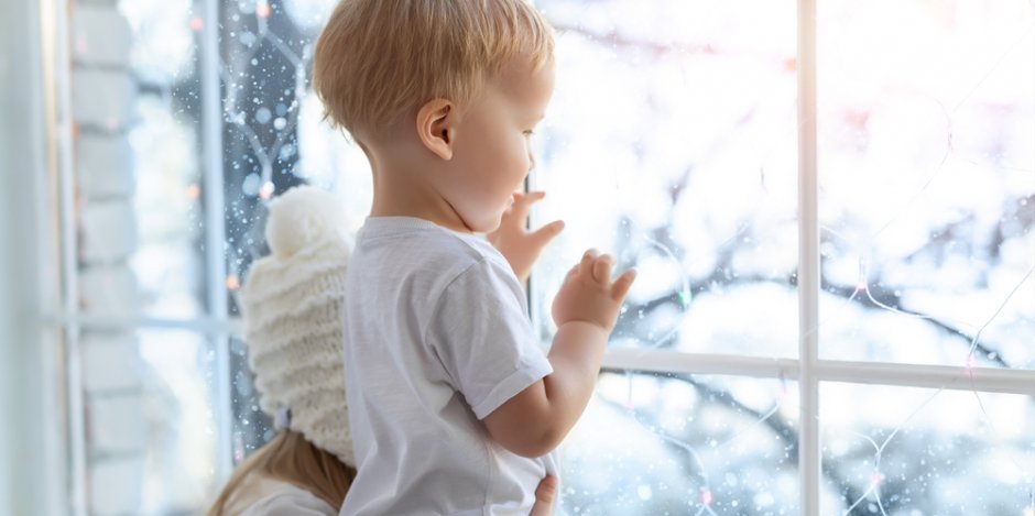 two children looking out window during winter